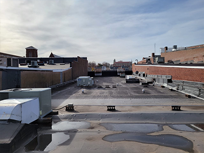 Flat commercial rooftop with HVAC units showing areas where water has pooled up