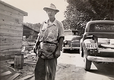 Old black-and-white photo of Bert Dorr standing near work vehicles at job site