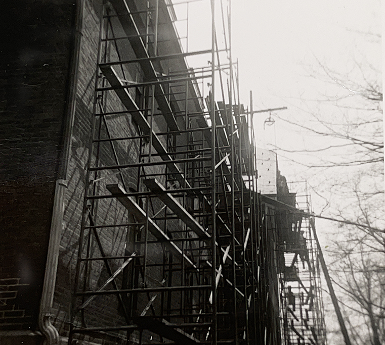 Black-and-white photo of a brick building with scaffolding 