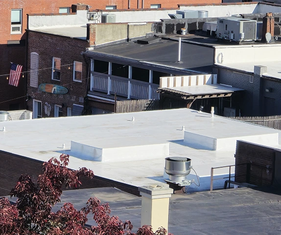Flat rooftop with white coating among nearby brick buildings.