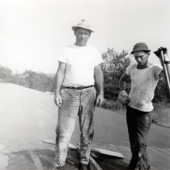 Old black-and-white photo of workers performing maintenance on a commercial rooftop